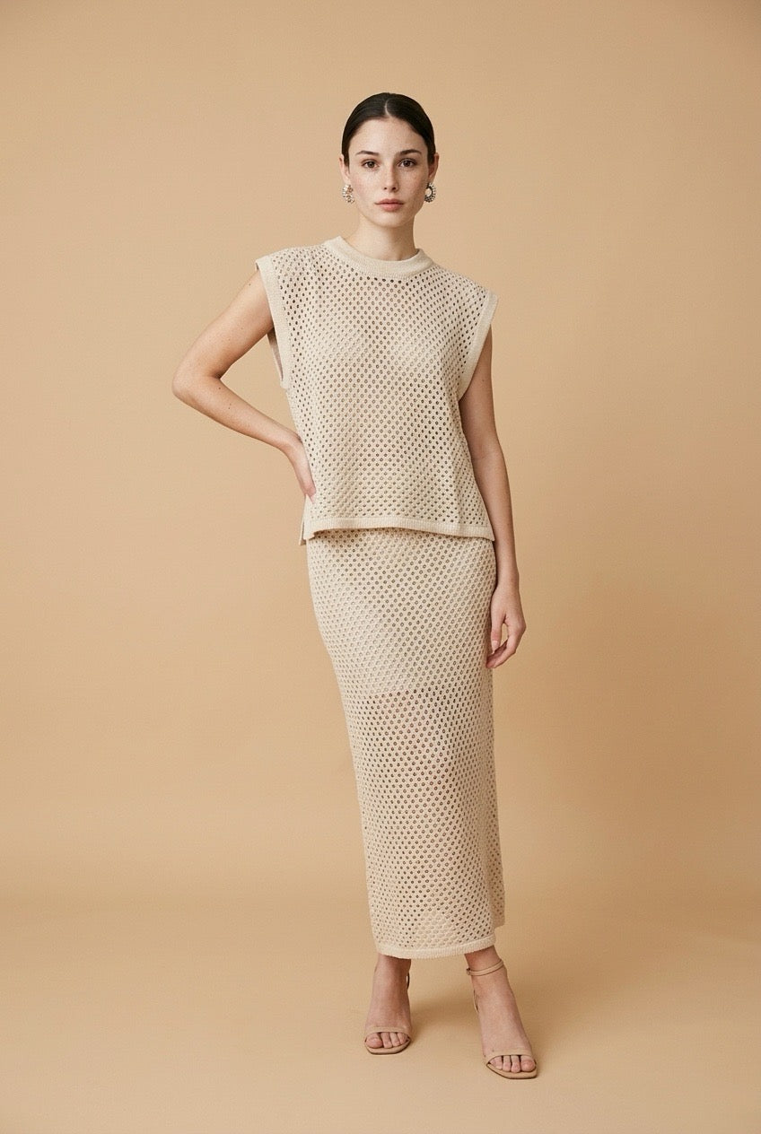 Model wearing the beige Alba set featuring a sleeveless open-knit crewneck vest top and a matching open-knit midi skirt
