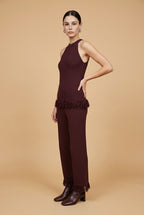 A woman wearing the Set Bérgamo knit two-piece set in deep burgundy, featuring a sleeveless halter top and straight-leg trousers with fringe hem details.