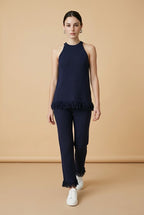 A woman wearing the Set Bérgamo knit two-piece set in navy blue, featuring a sleeveless halter top and straight-leg trousers with fringe hem details.
