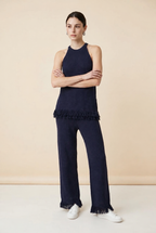 A woman wearing the Set Bérgamo knit two-piece set in navy blue, featuring a sleeveless halter top and straight-leg trousers with fringe hem details.