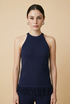 A woman wearing the Set Bérgamo knit two-piece set in navy blue, featuring a sleeveless halter top and straight-leg trousers with fringe hem details.