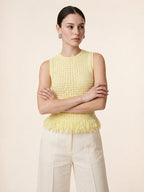 Woman wearing the Amelia sleeveless open-knit tank top in baby yellow with a fringed peplum hem