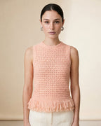 Woman wearing the Amelia sleeveless open-knit tank top in soft pink with a fringed peplum hem