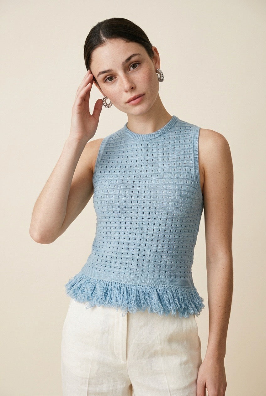 Woman wearing the Amelia sleeveless open-knit tank top in light blue with a fringed peplum hem