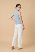 Woman wearing the Amelia sleeveless open-knit tank top in light blue with a fringed peplum hem