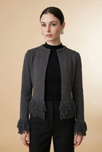 A woman wearing the open-front Cervinia knit cardigan in grey, featuring textured fringe trim along the hemline and sleeve cuffs.