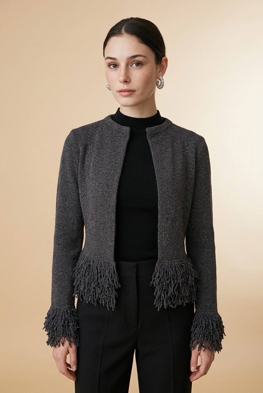 A woman wearing the open-front Cervinia knit cardigan in grey, featuring textured fringe trim along the hemline and sleeve cuffs.