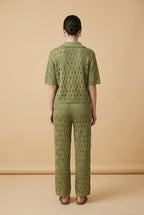A woman wearing the Set Positano open-knit two-piece set in olive green, featuring a collared polo top and matching wide-leg trousers.
