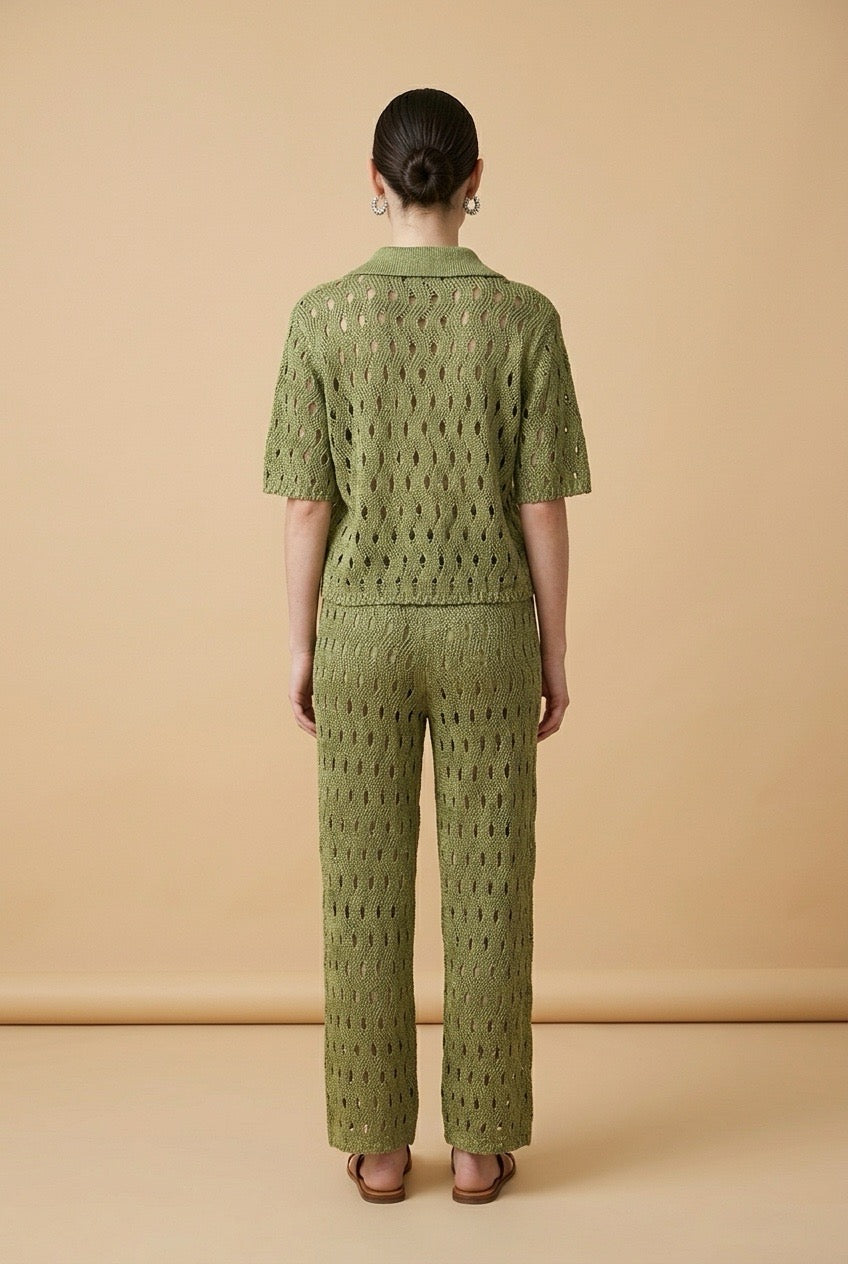 A woman wearing the Set Positano open-knit two-piece set in olive green, featuring a collared polo top and matching wide-leg trousers.