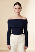 A woman wearing the Top Lecce off-the-shoulder knit top in navy blue, showing its sleek fitted silhouette.