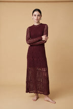 A woman wearing the chic long-sleeved Jackie midi dress in burgundy, accentuating its intricate geometric lace knit patterns.