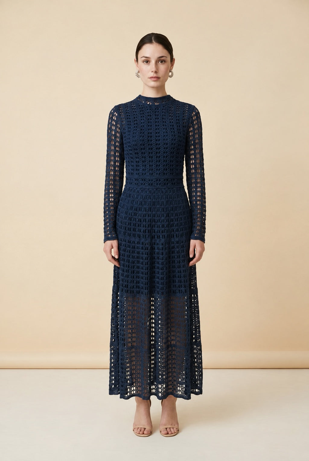 A woman wearing the elegant long-sleeved Jackie midi dress in navy blue, highlighting its intricate geometric lace knit patterns.