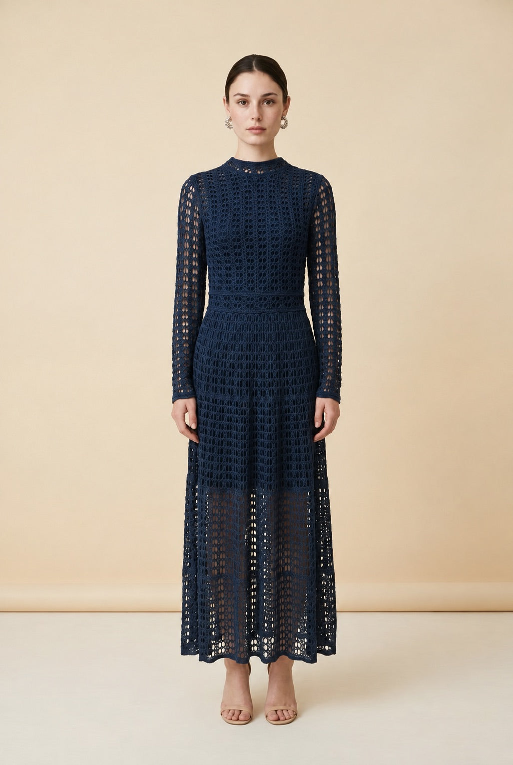 A woman wearing the elegant long-sleeved Jackie midi dress in navy blue, highlighting its intricate geometric lace knit patterns.