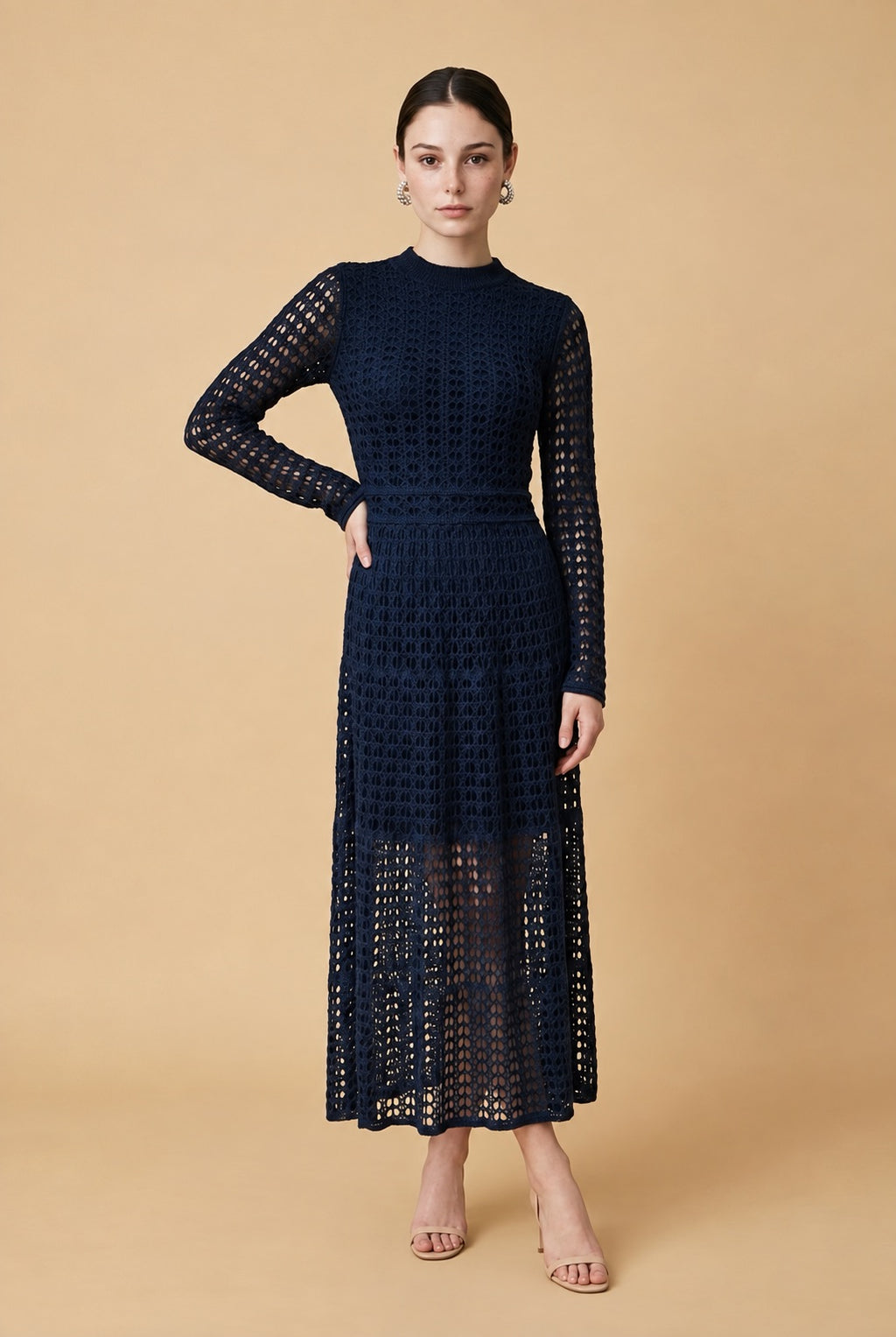 A woman wearing the elegant long-sleeved Jackie midi dress in navy blue, highlighting its intricate geometric lace knit patterns.