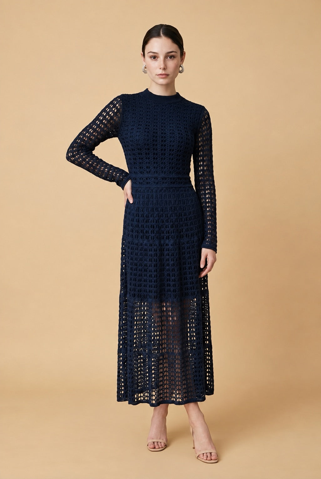 A woman wearing the elegant long-sleeved Jackie midi dress in navy blue, highlighting its intricate geometric lace knit patterns.
