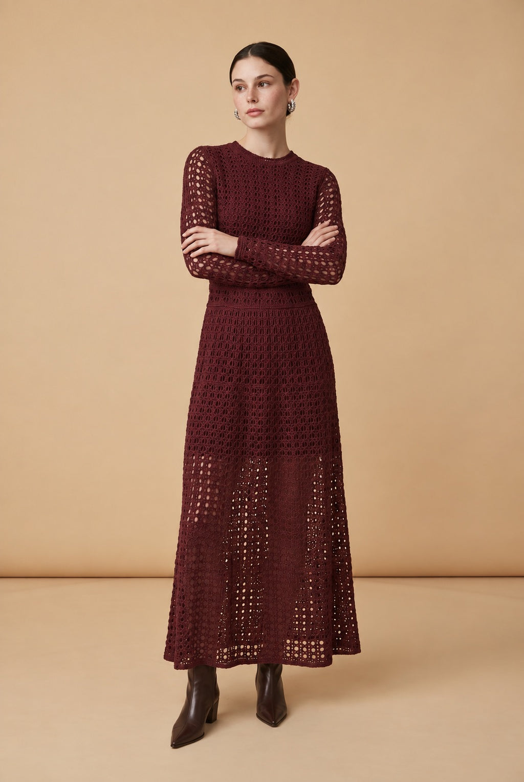 A woman wearing the chic long-sleeved Jackie midi dress in burgundy, accentuating its intricate geometric lace knit patterns.