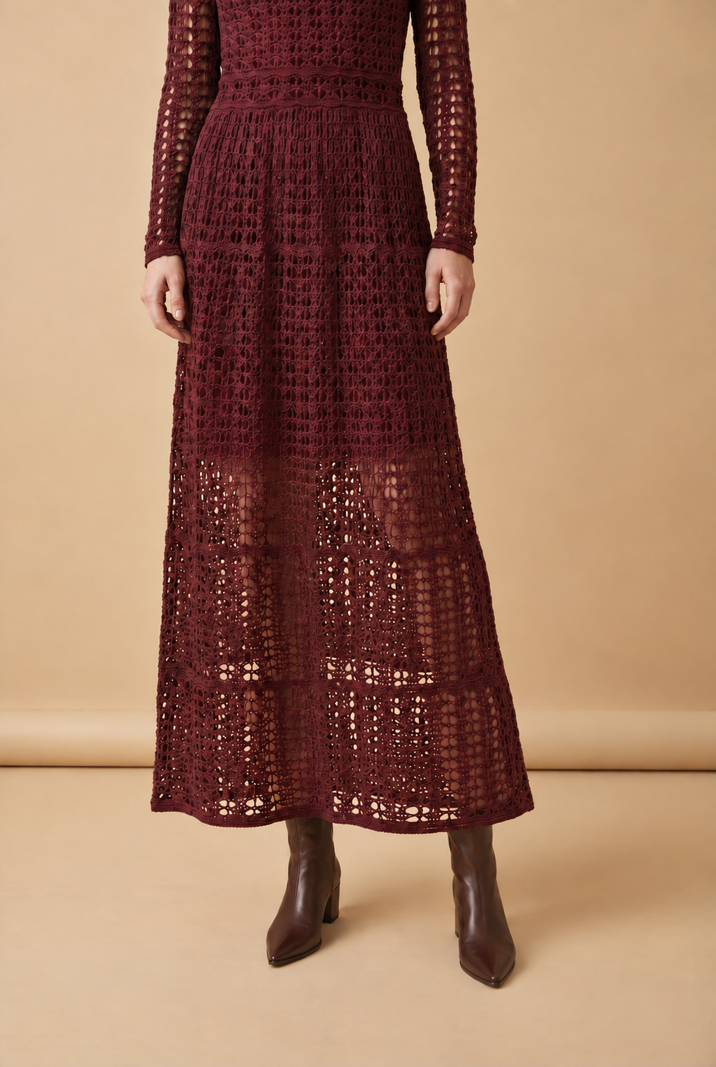A woman wearing the chic long-sleeved Jackie midi dress in burgundy, accentuating its intricate geometric lace knit patterns.