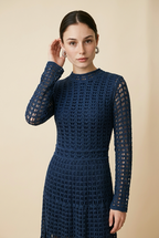A woman wearing the elegant long-sleeved Jackie midi dress in navy blue, highlighting its intricate geometric lace knit patterns.