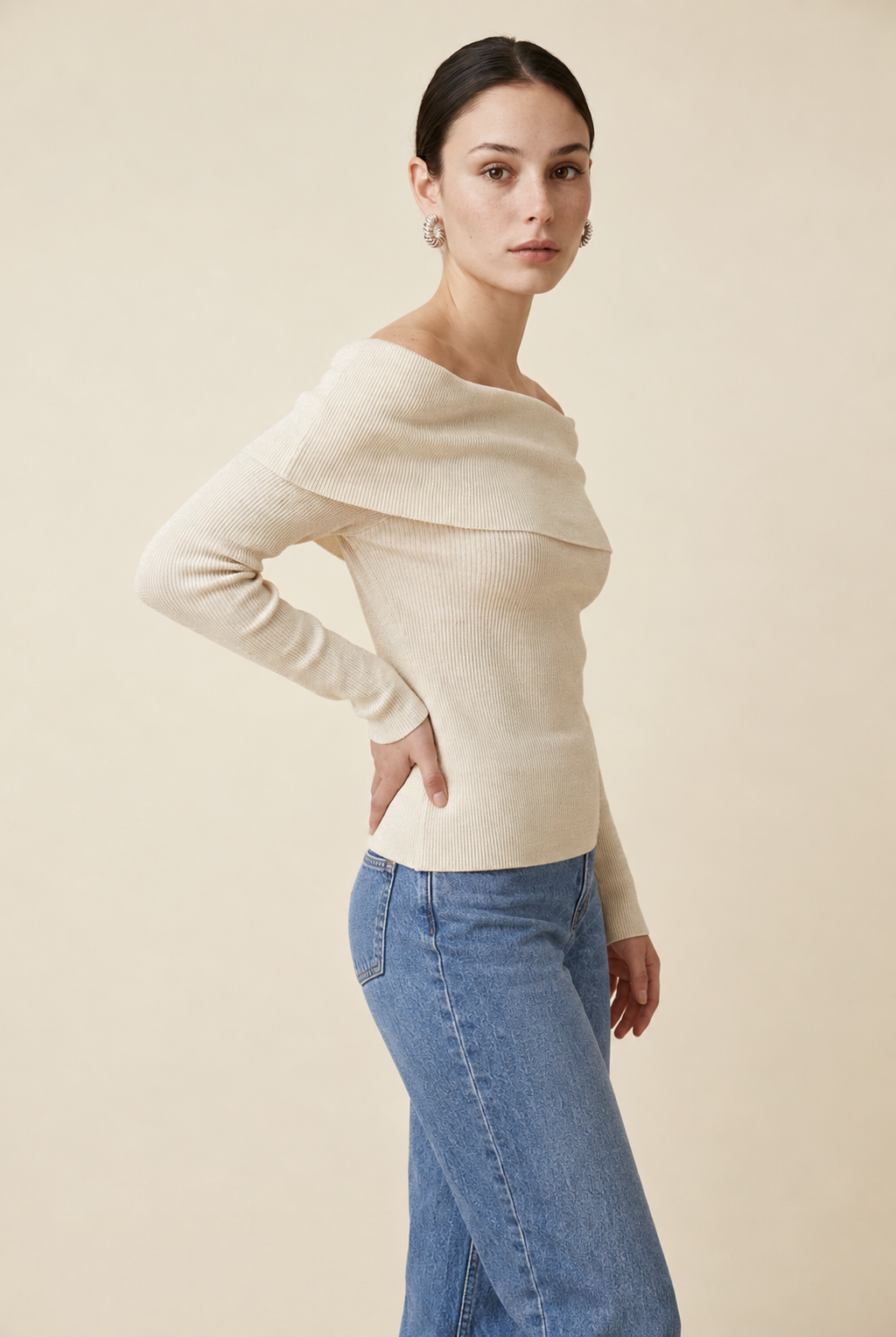 A woman wearing the Top Lecce off-the-shoulder knit top in ivory, featuring an elegant foldover detail across the shoulders.