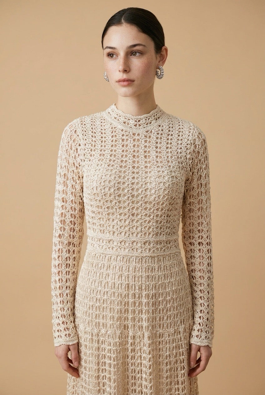 A woman wearing the sophisticated long-sleeved Jackie midi dress in bone, showcasing its intricate geometric lace knit patterns.