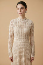A woman wearing the sophisticated long-sleeved Jackie midi dress in bone, showcasing its intricate geometric lace knit patterns.