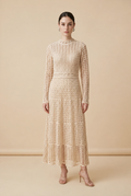 A woman wearing the sophisticated long-sleeved Jackie midi dress in bone, showcasing its intricate geometric lace knit patterns.