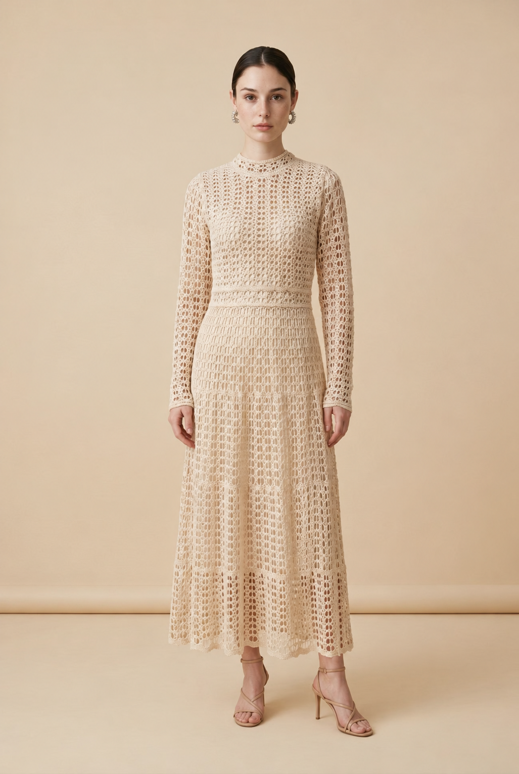 A woman wearing the sophisticated long-sleeved Jackie midi dress in bone, showcasing its intricate geometric lace knit patterns.