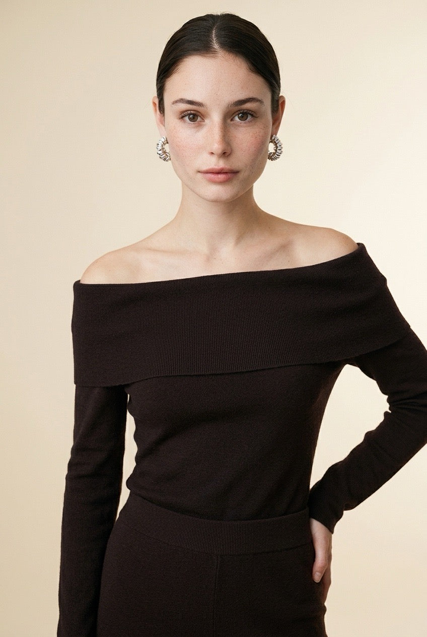 A woman wearing the Top Lecce off-the-shoulder knit top in black, featuring a foldover neckline and slim long sleeves.