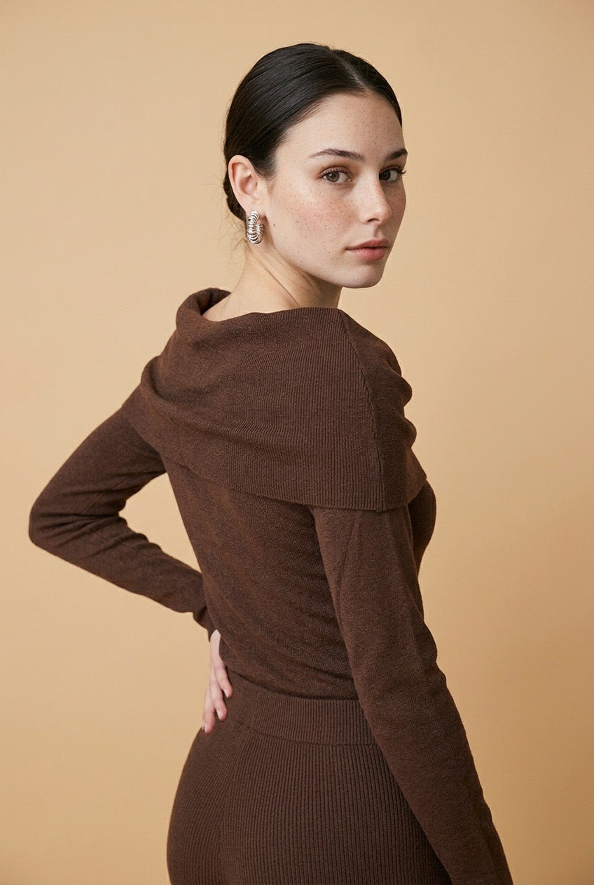 A woman wearing the Top Lecce off-the-shoulder knit top in deep brown, styled for a chic modern look.