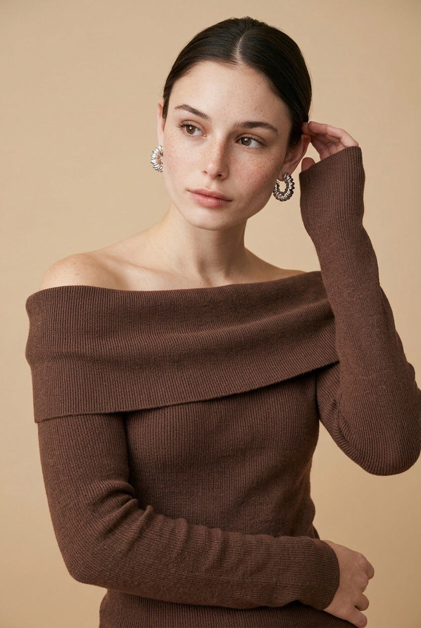 A woman wearing the Top Lecce off-the-shoulder knit top in deep brown, styled for a chic modern look.
