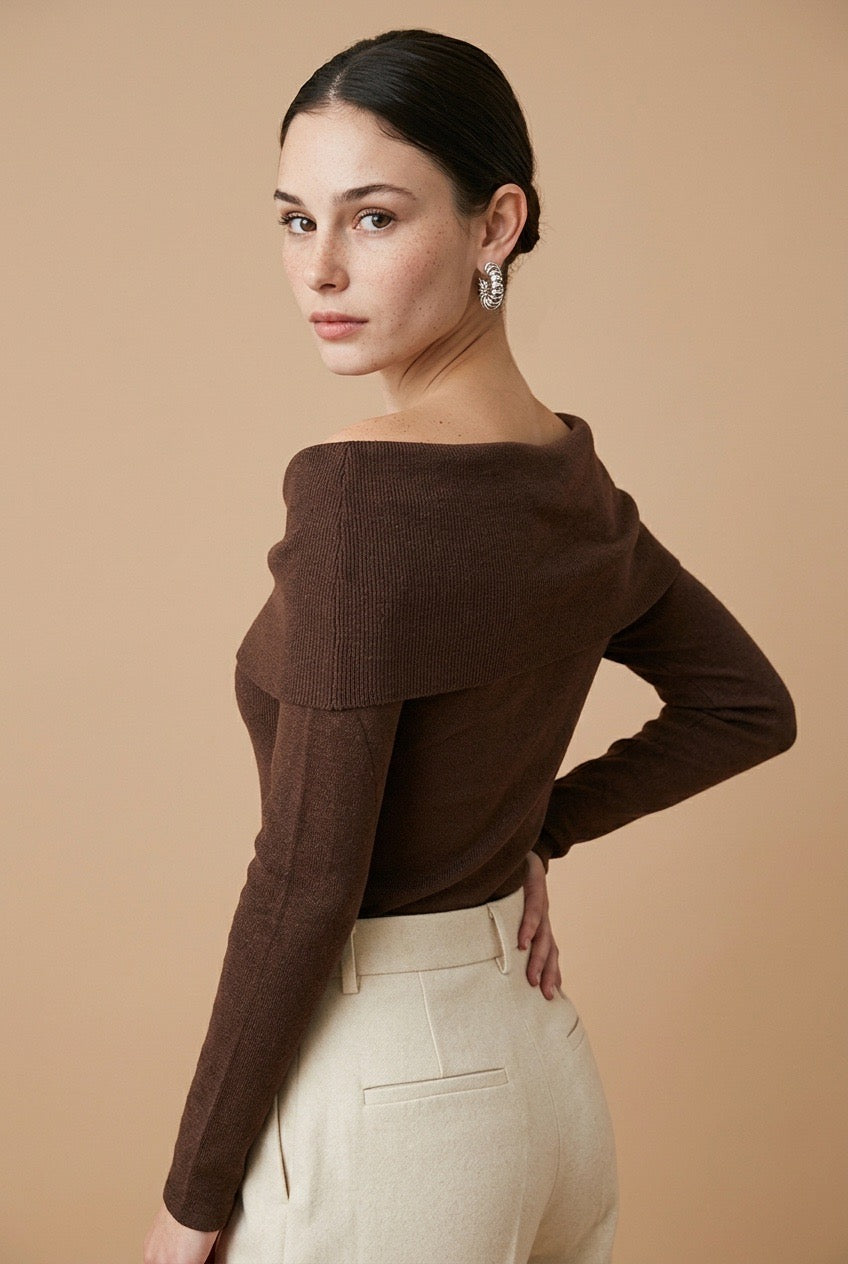 A woman wearing the Top Lecce off-the-shoulder knit top in deep brown, styled for a chic modern look.