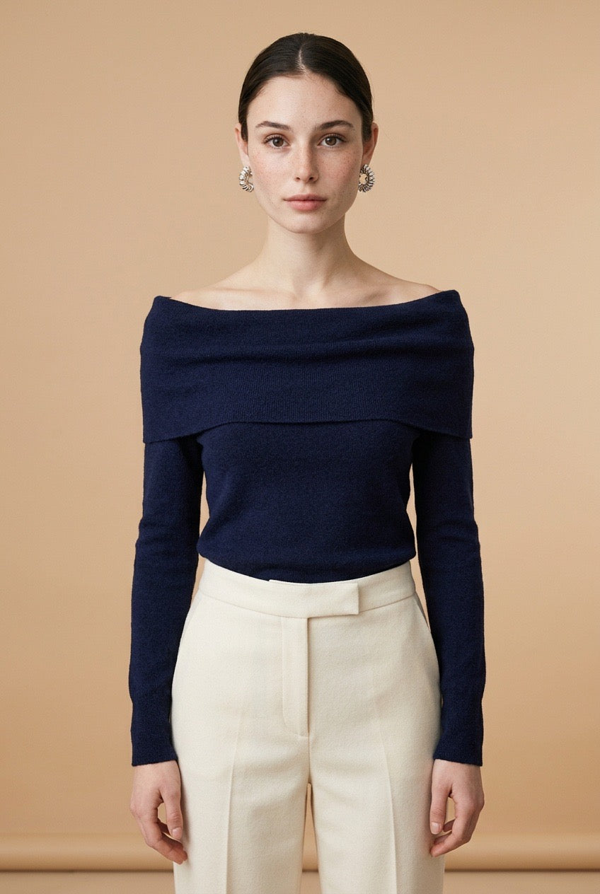 A woman wearing the Top Lecce off-the-shoulder knit top in navy blue, showing its sleek fitted silhouette.
