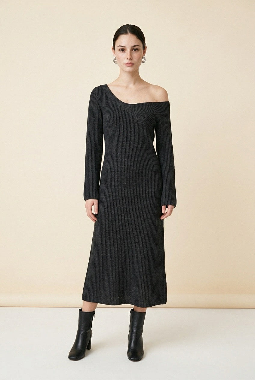A woman wearing the long-sleeve Mantova Dress in black, featuring an asymmetrical off-the-shoulder neckline and vertical ribbed texture.