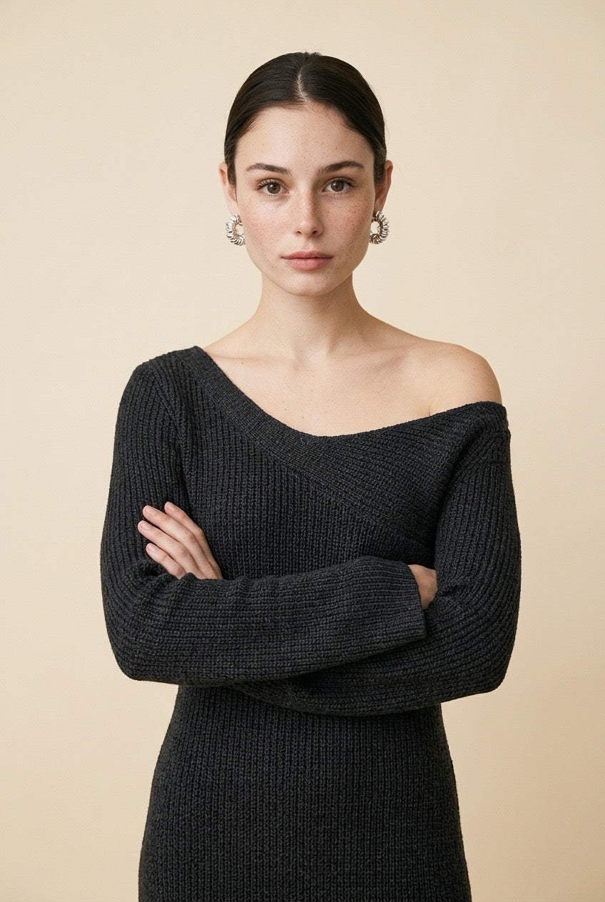 A woman wearing the long-sleeve Mantova Dress in black, featuring an asymmetrical off-the-shoulder neckline and vertical ribbed texture.