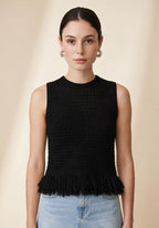 Model wearing the black Nerano sleeveless knit top with a crew neckline, textured eyelet pattern, and fringe hem trim
