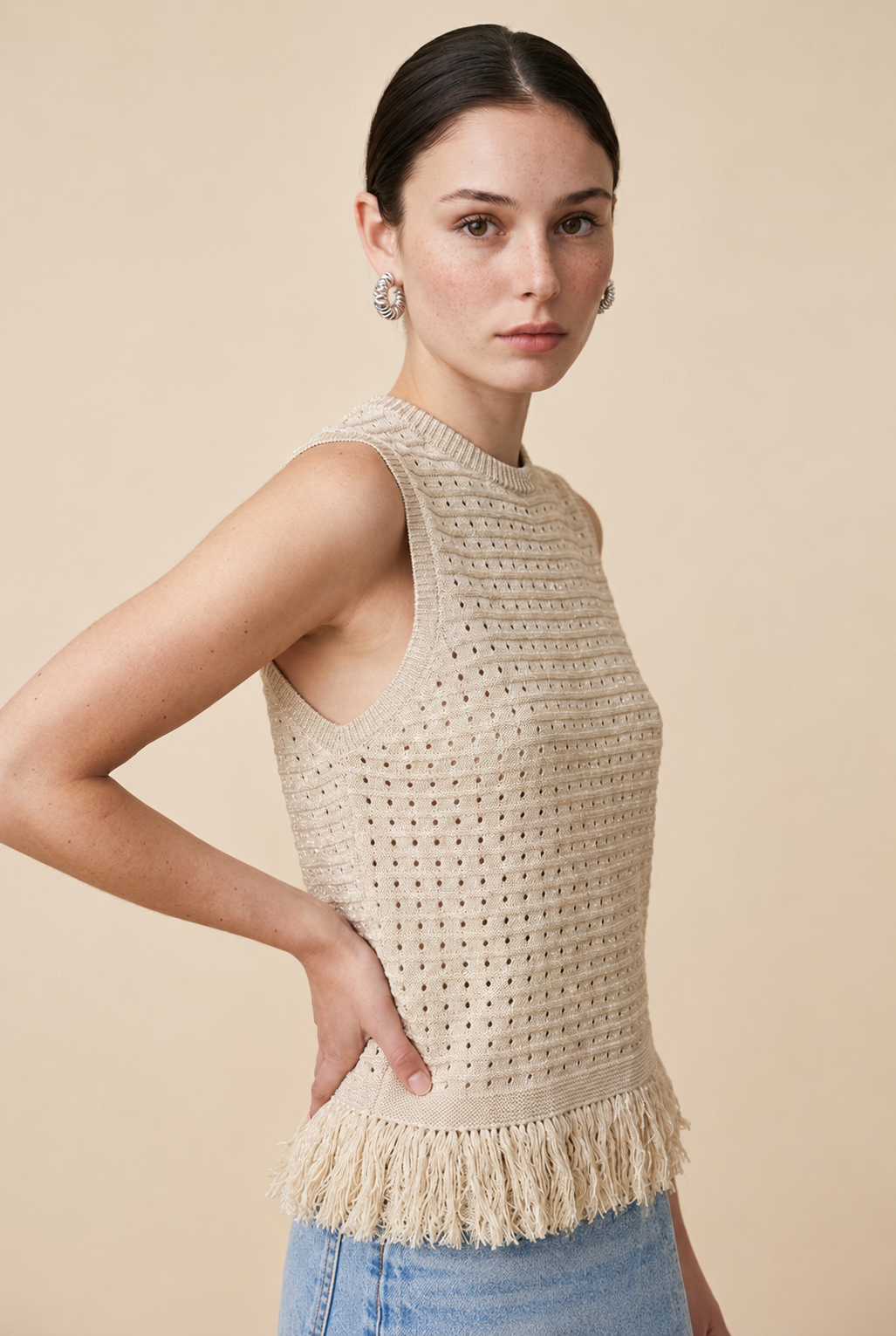 Nerano sleeveless knit top in beige featuring a crew neck, open-knit texture, and fringe hem trim
