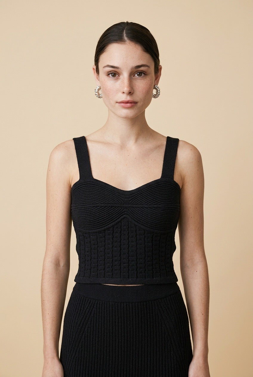 Model wearing the black Siena knit tank top featuring wide shoulder straps, a sweetheart neckline, ribbed bust detail, and a textured corset-style bodice