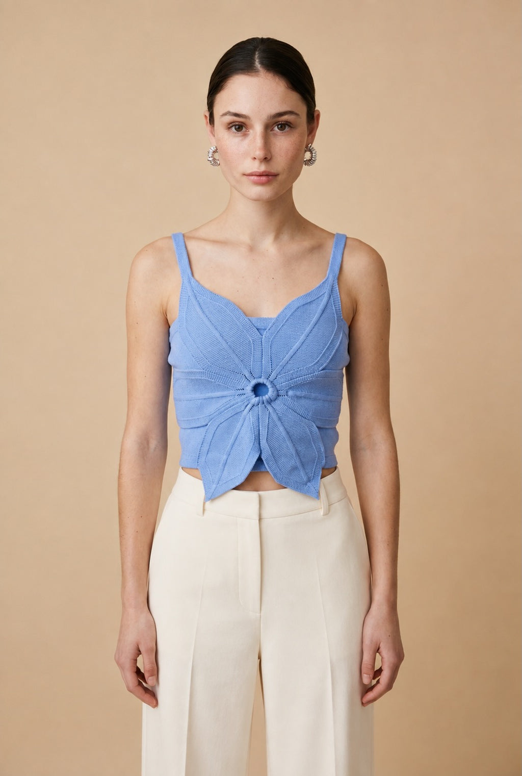Woman wearing the Top Bloom knit crop top in cornflower blue with 3D flower petal detail and thin straps