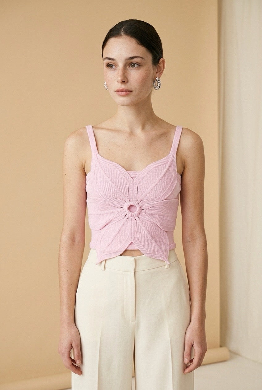Woman wearing the Top Bloom knit crop top in soft pink with 3D flower petal design and thin straps