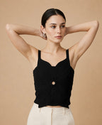 A young woman wearing a black sleeveless, cropped knit top with a central circular ring detail and a pointed asymmetric hem